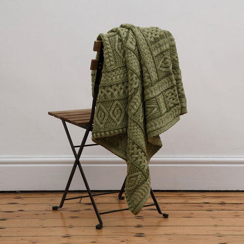 Irish Home Decor - The green Celtic Two Tone Aran Throw Blanket hanging wooden on a chair on a wooden floor.