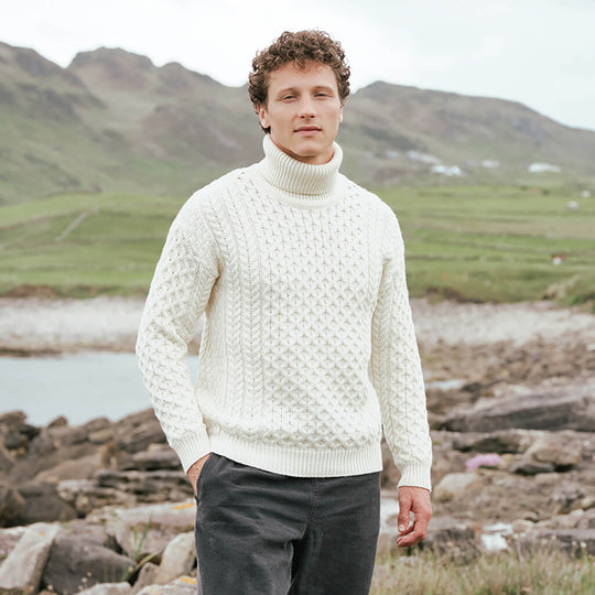Image featuring the Men's Signature Fisherman Turtleneck Wool Sweater in cream, crafted from premium wool with authentic Irish fisherman cable knit patterns and a warm ribbed turtleneck, showcasing timeless Irish craftsmanship in a scenic coastal landscape.