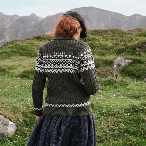 Back view of the Women's Fair Isle Cable Knit Sweater in army green, crafted with authentic cable knit textures and traditional Fair Isle motifs across the yoke and hem, showcased in a rugged Irish countryside setting.