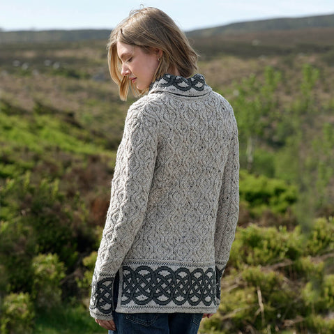 Woman wearing a grey patterned Aran sweater standing in a natural landscape