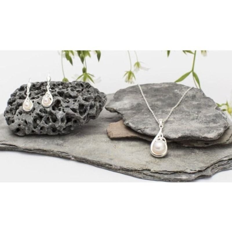 The Trinity Knot Classic Pearl Jewelry Set featuring a pendant necklace and matching earrings. The pendant has a teardrop design with a central freshwater pearl and silver trinity knot accents, while the earrings mirror the pendant's shape.