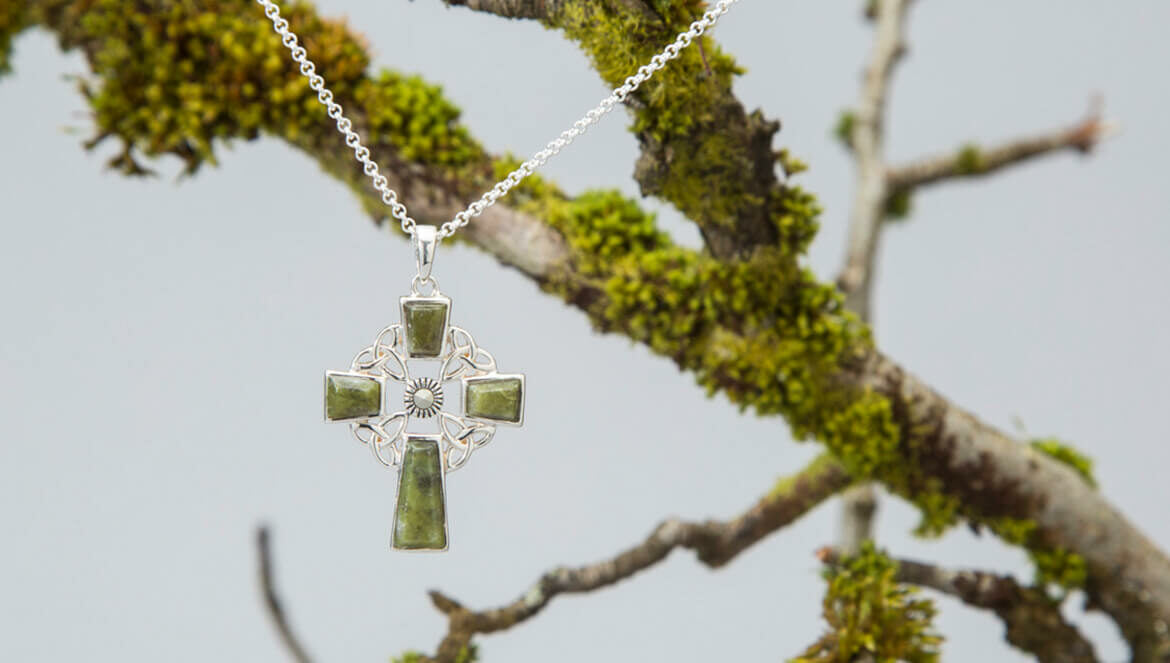 Marcasite & Connemara Marble Celtic Cross. A silver Celtic cross pendant with Connemara Marble accents, set on a delicate chain. The design features intricate knotwork and ornate details, showcasing traditional Celtic artistry.