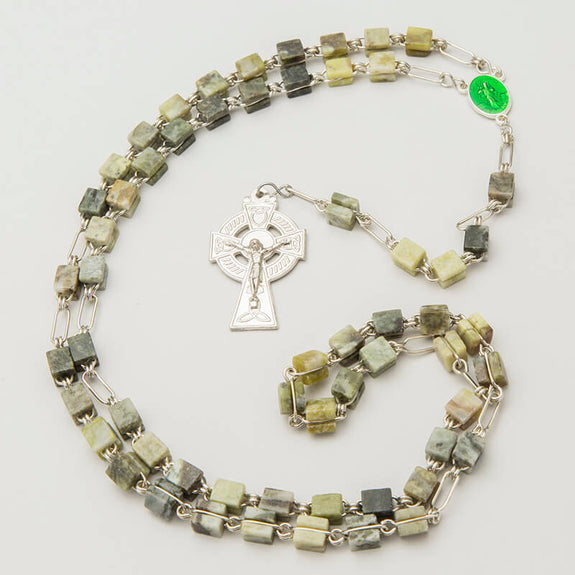 Connemara Marble Rosary Beads. A rosary made of square Connemara Marble beads strung together with silver chain links. A silver cross pendant is attached, featuring a decorative design.