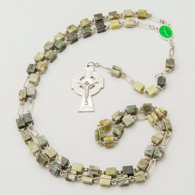 Connemara Marble Rosary Beads. A rosary made of square Connemara Marble beads strung together with silver chain links. A silver cross pendant is attached, featuring a decorative design.