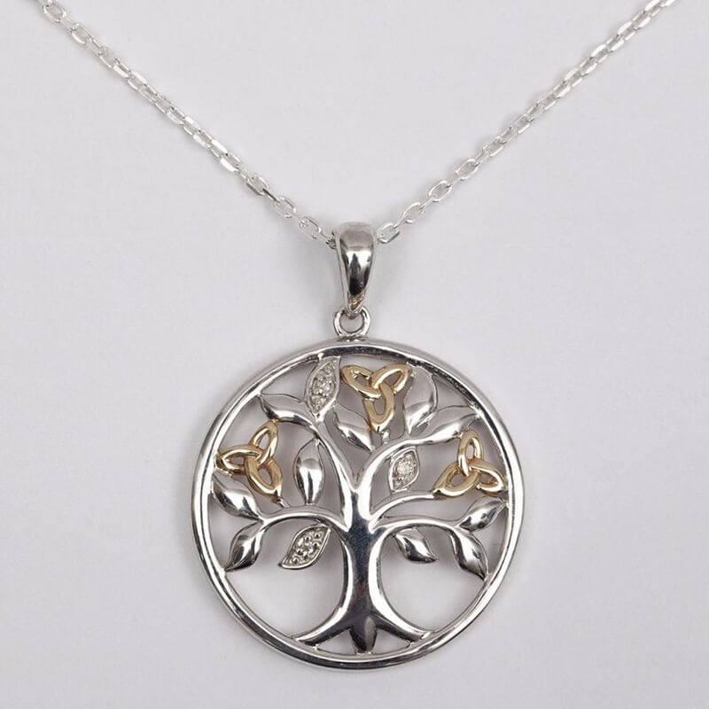 Silver pendant necklace featuring a tree of life design with intricate branches, set within a circular frame. The pendant hangs from a delicate chain.