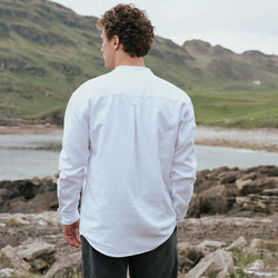 Back view of the Classic Grandad Shirt in white, crafted with a traditional Irish grandad collar and timeless relaxed silhouette, showcased against Ireland's scenic coastline and countryside.