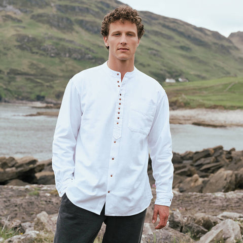 Image featuring the Classic Grandad Shirt in white, crafted with a traditional Irish grandad collar, button-front placket, and timeless relaxed fit, showcased along Ireland's scenic coastline.