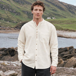 Image featuring the Classic Grandad Shirt in stone, crafted with a traditional Irish grandad collar, button-front placket, chest pocket, and timeless relaxed silhouette, showcasing classic Irish style against a scenic coastal landscape.