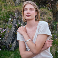 Image featuring the Celtic Warrior Bangle, crafted with intricate Celtic knotwork and traditional Irish design details inspired by ancient Irish heritage, elegantly showcased against a scenic coastal landscape.