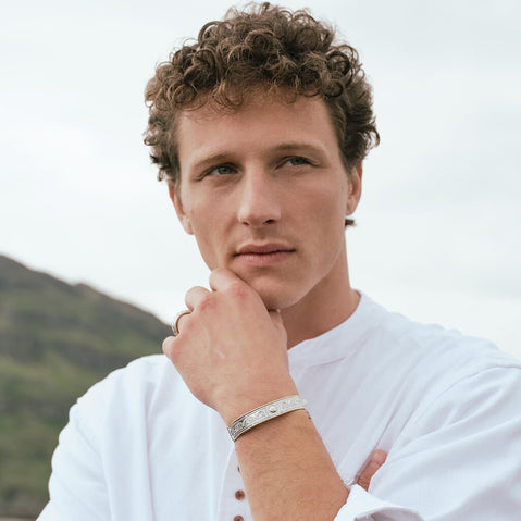 Image featuring the Celtic Warrior Bangle, crafted with intricate Celtic knotwork and traditional Irish design details inspired by ancient Irish heritage, showcased in a rugged coastal setting.
