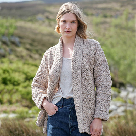 Woman wearing a beige knitted Aran cardigan in a natural setting