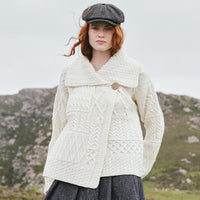 Image featuring the Women's One Button Aran Cardigan in cream, crafted with authentic Irish Aran cable knit patterns, a statement shawl collar, and classic one-button closure, showcasing timeless Irish craftsmanship in a scenic countryside setting.
