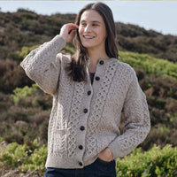 Woman wearing a beige Womens Traditional Cable Knit Aran Cardigan in a natural setting