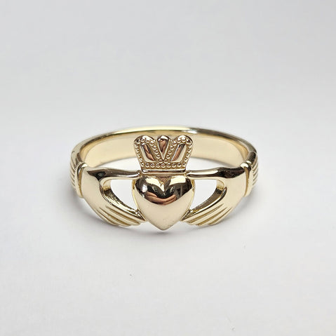Gold Claddagh ring on a light gray background