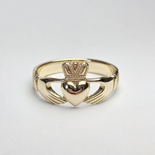Gold Claddagh ring on a light gray background