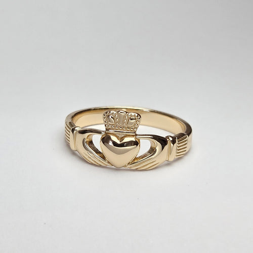Gold Claddagh ring on a light gray background