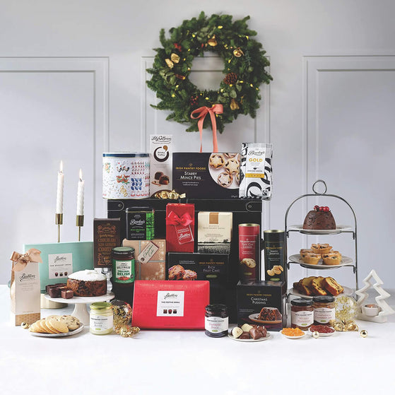 Assorted holiday gifts and treats on a table with a wreath in the background.