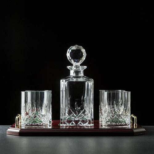 Galway Crystal Longford Decanter and Glasses Gift Set displayed on a dark wooden tray, featuring a faceted crystal decanter with stopper and two matching cut-crystal glasses against a black background.