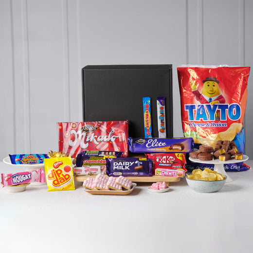 Classic Irish Treats Gift Box. Assorted confectionery items including Irish candy bars and snacks on a white surface with a gray background.