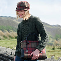 Woman holding a plaid bag outdoors with mountains in the background