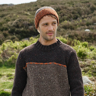 Man wearing a brown knitted sweater and hat standing in a natural setting