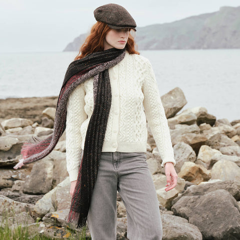 Women's Alpaca Islander Scarf in Cranberry, crafted from luxuriously soft alpaca wool with a rich textured weave, styled with a traditional Irish Aran sweater and flat cap along the rugged Irish coastline.