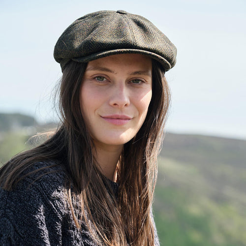 Woman wearing a dark green flat cap with a blurred natural background