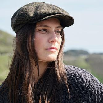 Woman wearing a flat cap outdoors with a blurred natural background