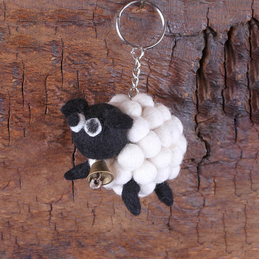 Sheep-shaped keychain with a bell on a wooden surface