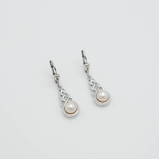 Pair of silver earrings with pearl drops on a light gray background