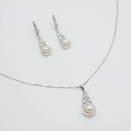 Pearl necklace and earrings set on a light gray background