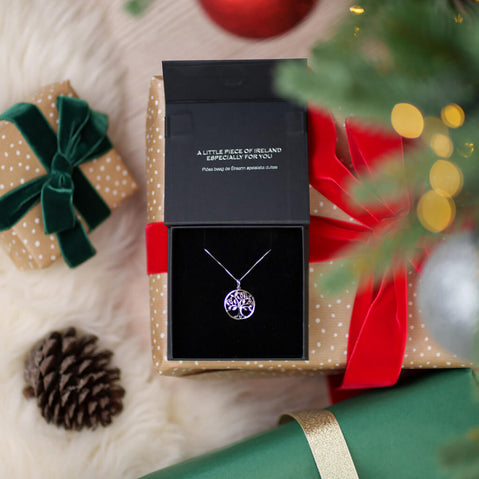 Tree of Life necklace in a gift box with Christmas decorations in the background