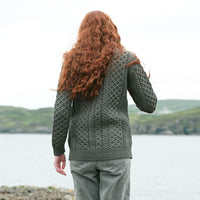 Back view of The Banna Aran Cardigan in Tundra, crafted with authentic Irish Aran cable knit patterns and timeless heritage-inspired styling, showcasing the intricate knit design against a scenic Irish coastal backdrop.