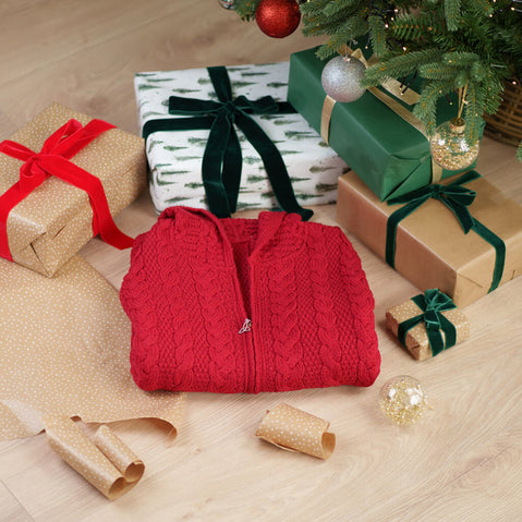 Women's Hooded Aran Zipper Classic Coat in red with Celtic trinity knot zipper pull displayed among wrapped Christmas gifts under decorated tree