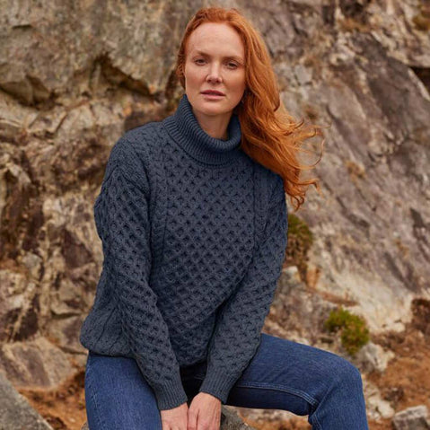 Woman wearing a charcoal Women's Turtleneck Sweater sitting against a rocky background