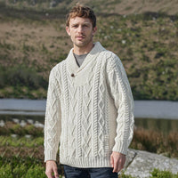 Man wearing a cream knitted sweater standing outdoors with a natural background