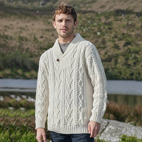 Man wearing a cream knitted sweater standing outdoors with a natural background