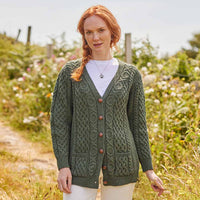 Woman wearing a green Women's Classic Aran Boyfriend Button-Front Cardigan in a field with wildflowers