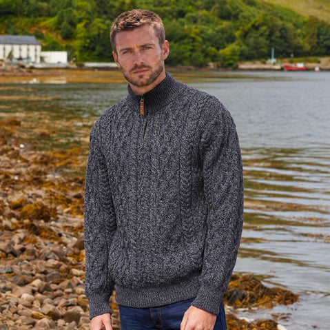 Image featuring the Men's Signature Half Zip Irish Wool Sweater in cormorant, crafted from premium Irish wool with authentic cable knit patterns and a practical half-zip funnel neck, showcasing timeless Irish craftsmanship against a scenic coastal landscape.