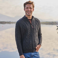 Man wearing a charcoal Men's Fisherman Full-Zip Aran Cardigan by a lake