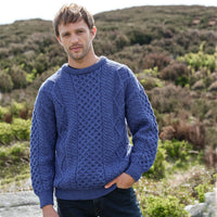 Man wearing a cobalt blue Men's Fisherman Lightweight Crew Neck Heritage Sweater standing in a natural landscape.