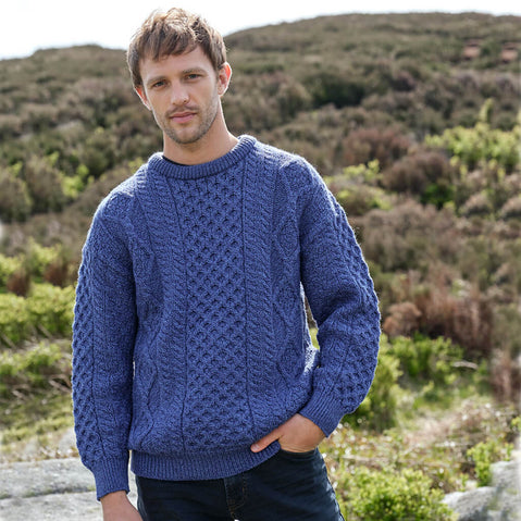 Man wearing a cobalt blue Men's Fisherman Lightweight Crew Neck Heritage Sweater standing in a natural landscape.