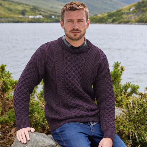 Image featuring the Men's Fisherman Lightweight Crew Neck Heritage Sweater in damson, crafted with authentic Irish fisherman cable knit patterns and a timeless crew neck silhouette, showcasing traditional Irish craftsmanship against a scenic lakeside landscape inspired by Ireland's rugged countryside.