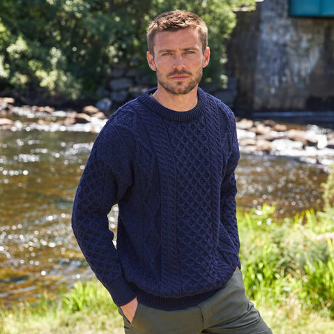 Image featuring the Men's Fisherman Lightweight Crew Neck Heritage Sweater in navy, crafted with authentic Irish fisherman cable knit patterns and a timeless crew neck silhouette, showcasing traditional Irish craftsmanship in a scenic riverside countryside setting.