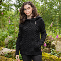 Woman wearing a black cable knit hoodie in a forest setting
