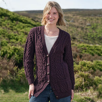 Woman wearing a dark purple Aran cardigan with intricate patterns outdoors.