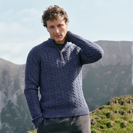 Image featuring the Men's Traditional Half Zip Cable Knit Sweater in indigo, crafted with authentic Irish cable knit patterns and a practical half-zip neckline, inspired by Ireland's rich knitting heritage and rugged countryside.