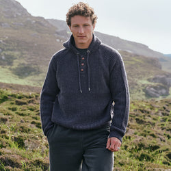 Image featuring the Men's Ribbed Hooded Sweater in indigo marl, crafted with a rich rib knit texture, drawstring hood, and button-front placket, inspired by traditional Irish knitwear and Ireland's scenic countryside.
