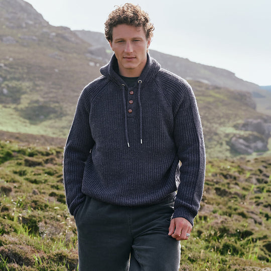 Image featuring the Men's Ribbed Hooded Sweater in indigo marl, crafted with a rich rib knit texture, drawstring hood, and button-front placket, inspired by traditional Irish knitwear and Ireland's scenic countryside.
