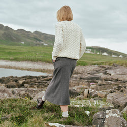 Image featuring the Irish Tweed Herringbone A-Line Skirt in gray, crafted from authentic Irish tweed with a timeless herringbone pattern and flattering A-line shape, showcasing classic Irish heritage style from a rear view against a rugged countryside backdrop.